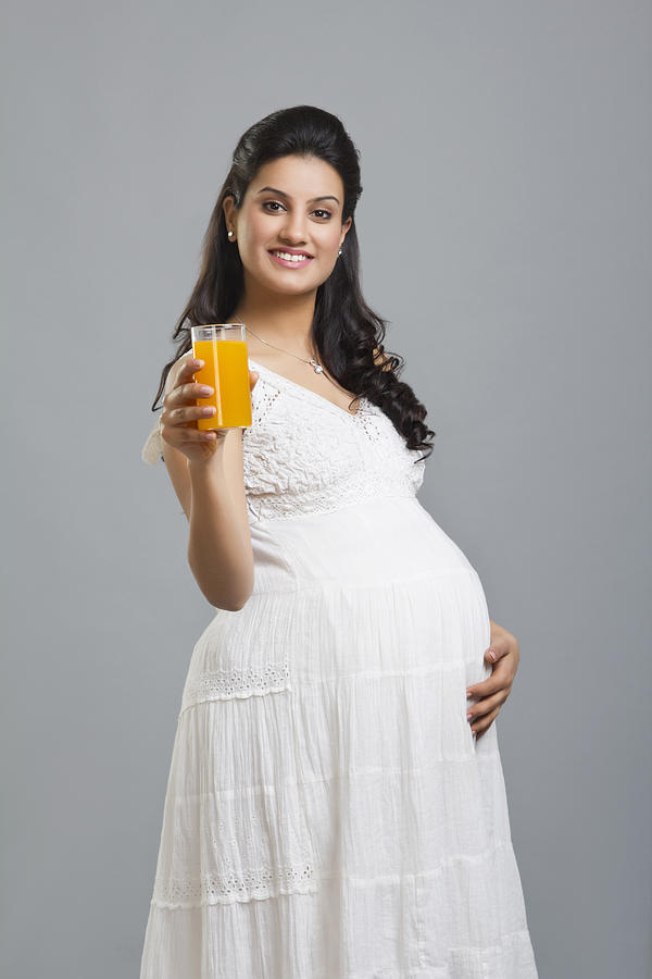 Portrait of a pregnant woman with a glass of orange juice #1 Photograph by IndiaPix/IndiaPicture