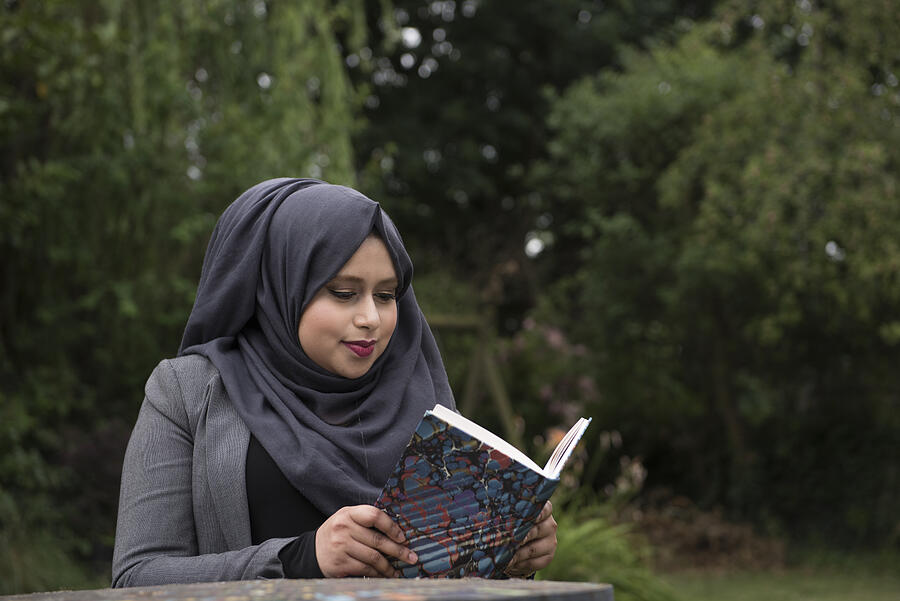 Portrait of a young lady wearing a hijab reading abook in the garden #1 Photograph by Richard Bailey