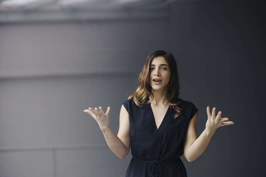 Portrait of gesturing young businesswoman against grey background #1 Photograph by Westend61