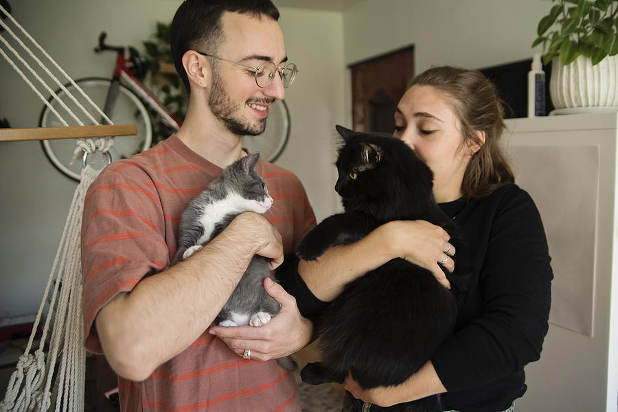 Portrait of millennial couple and newly adopted kitten at home. #1 Photograph by Martinedoucet