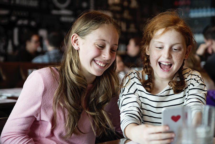 Preteens girls doing selfies at a restaurant table. #1 Photograph by Martinedoucet