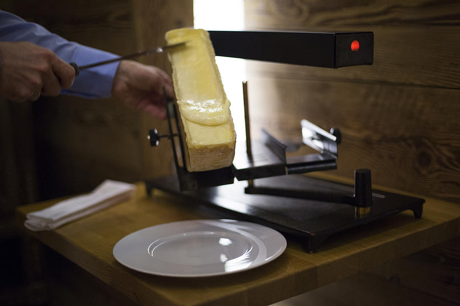 Raclette cheese on grill, Crans-Montana, Swiss Alps, Switzerland #1 Photograph by Sandy Aknine