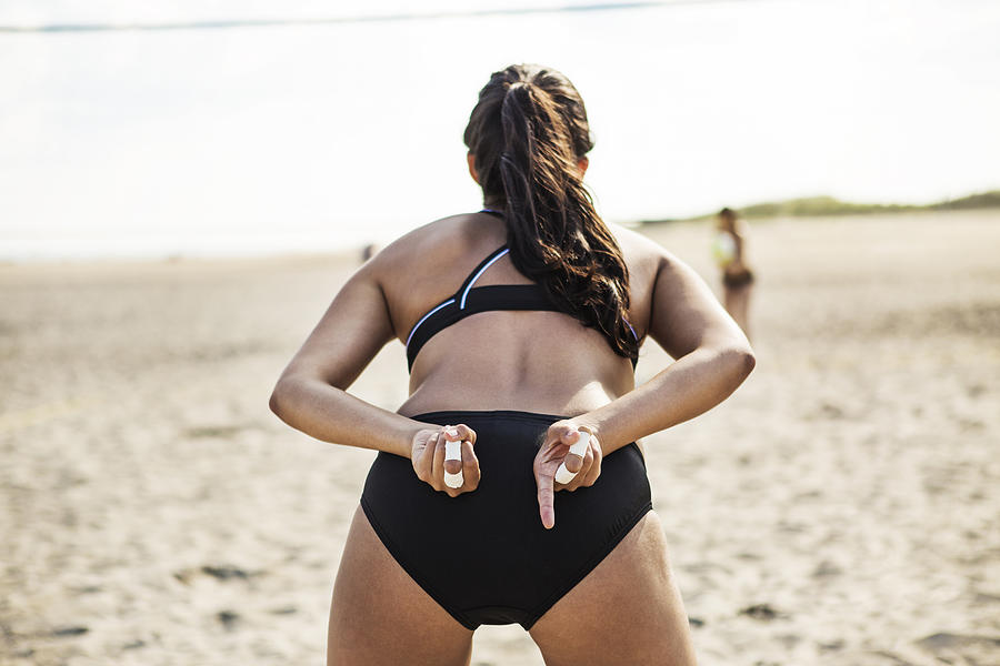Rear view of woman standing at beach while playing volleyball #1 Photograph by Cavan Images