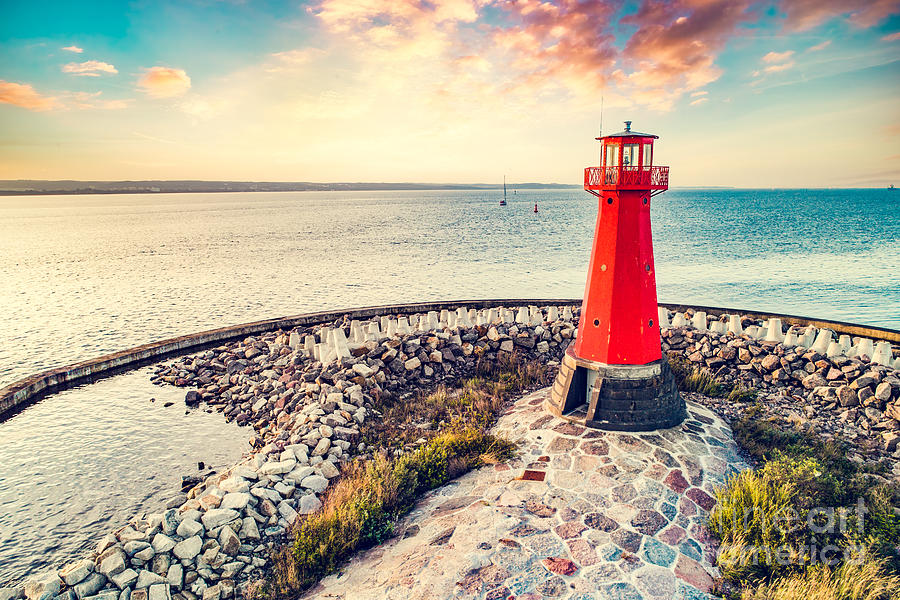 Red lighthouse on rocky harbor at sunset #1 Photograph by Michal Bednarek