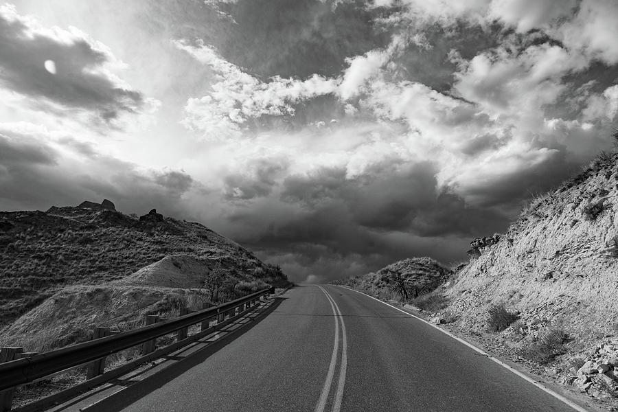 Road with clouds at Theodore Roosevelt National Park in North Dakota in black and white #1 Photograph by Eldon McGraw