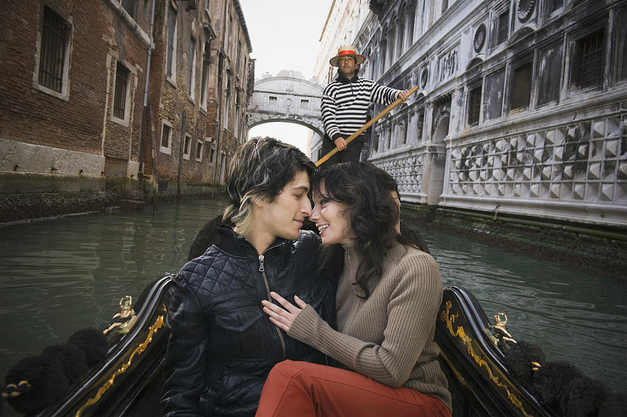 Romantic Italian couple riding in gondola through canal #1 Photograph by PBNJ Productions