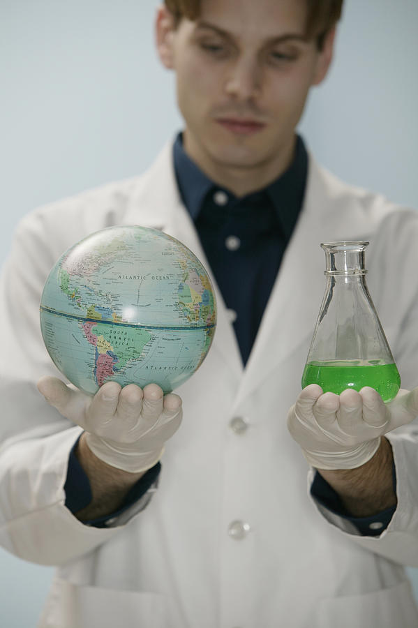 Scientist holding globe and beaker #1 Photograph by Comstock Images