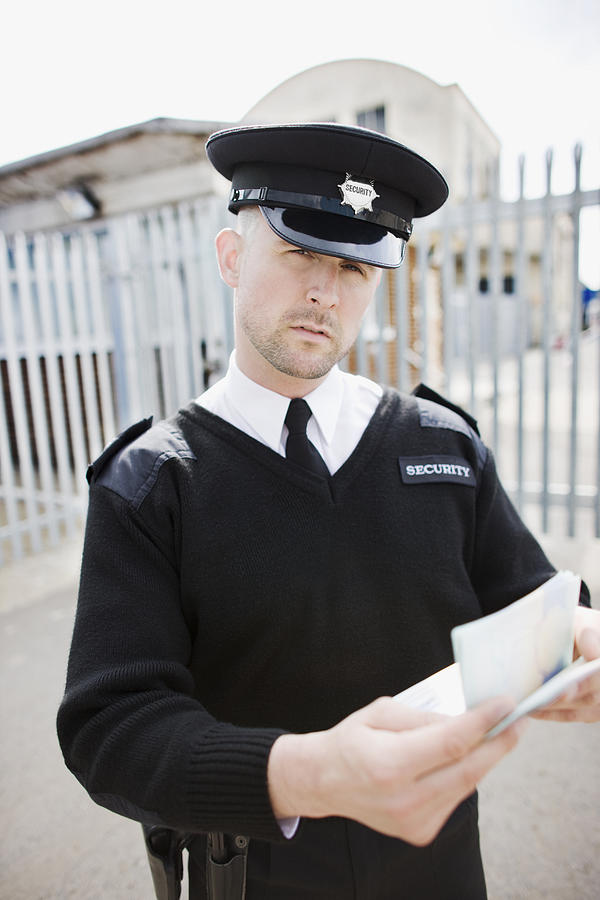 Security guard checking passport #1 Photograph by Paul Bradbury