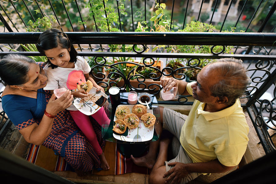Senior couple enjoying snacks in the balcony with granddaughter #1 Photograph by Mayur Kakade