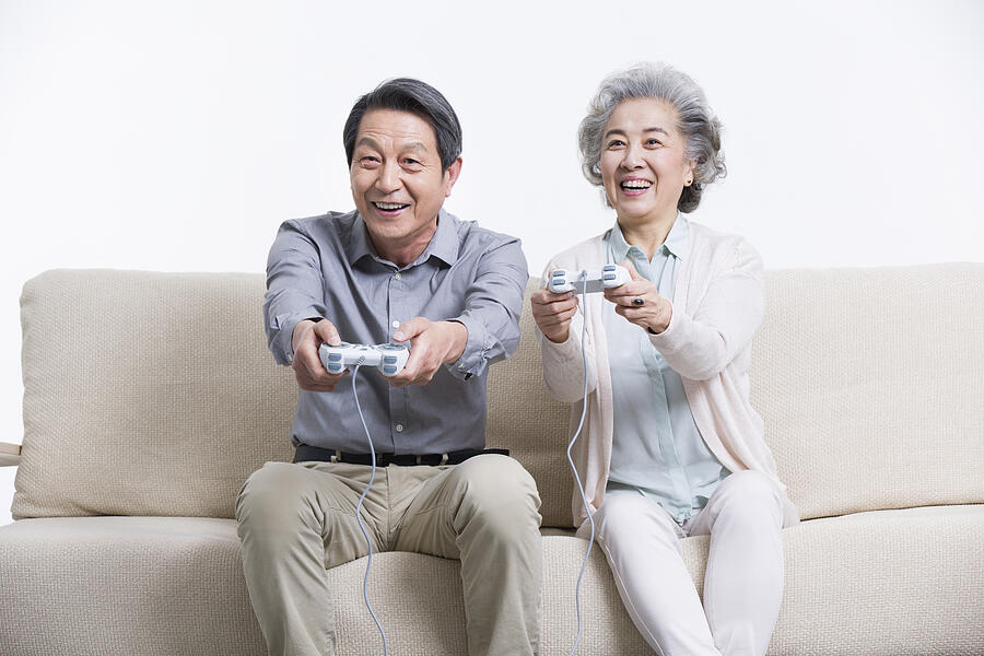Senior couple playing video game in living room #1 Photograph by BJI / Blue Jean Images