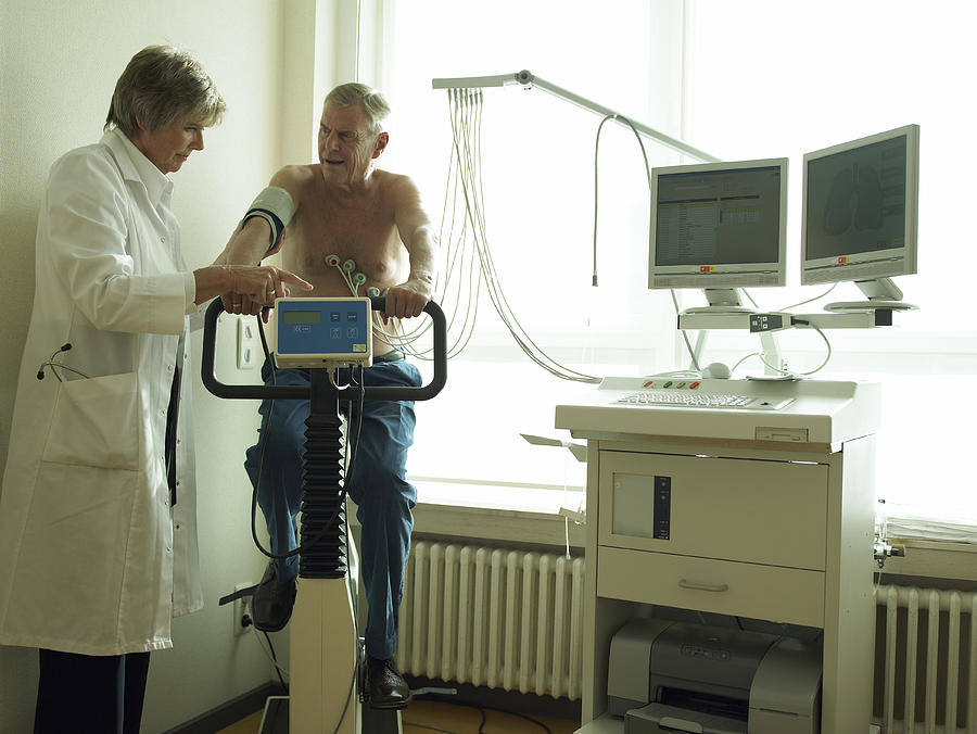 Senior female doctor by male patient having cardiology test #1 Photograph by Hans Neleman