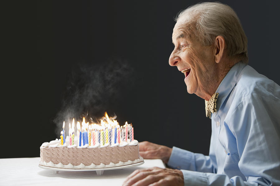 Senior Hispanic man blowing out birthday candles #1 Photograph by Jose Luis Pelaez Inc