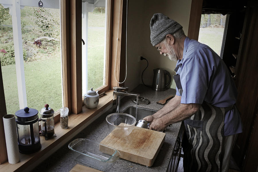 Senior man washing up dishes #1 Photograph by Rafael Ben-Ari