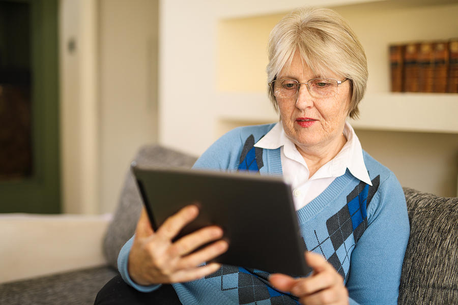Senior woman using digital tablet at home #1 Photograph by EmirMemedovski