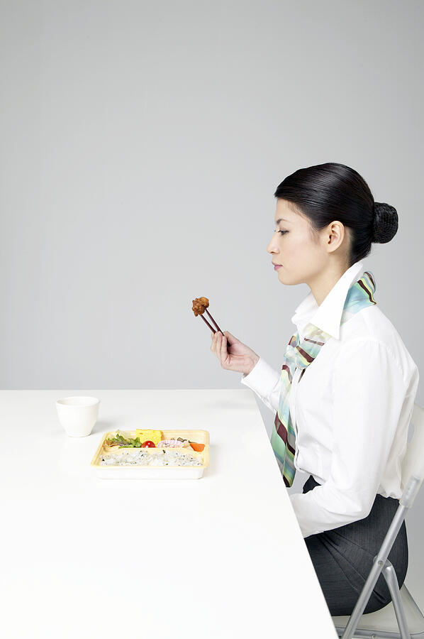 Side View of a Woman Sitting at a Table Eating Food With Chopsticks #1 Photograph by Mash