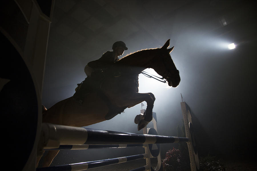 Silhouette of a horse and a rider jumping over hurdle #1 Photograph by Tomazl