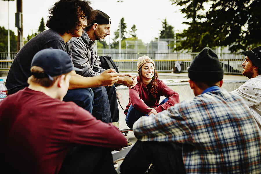 Skateboarders sitting in discussion in skate park #1 Photograph by Thomas Barwick