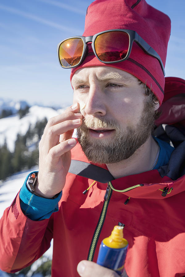 Skier applying sun cream on face #1 Photograph by Robert Niedring
