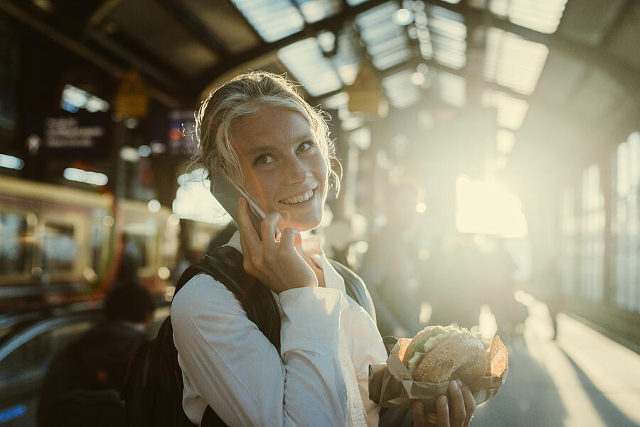 Smiling businesswoman eating a bagel. #1 Photograph by Guido Mieth