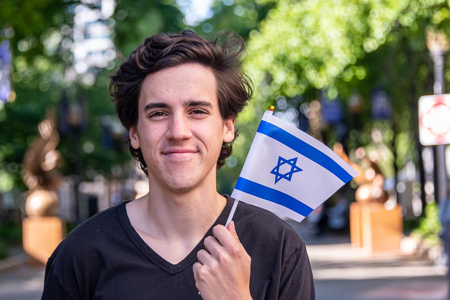 Smiling young man waving the Israeli flag #1 Photograph by Juanmonino