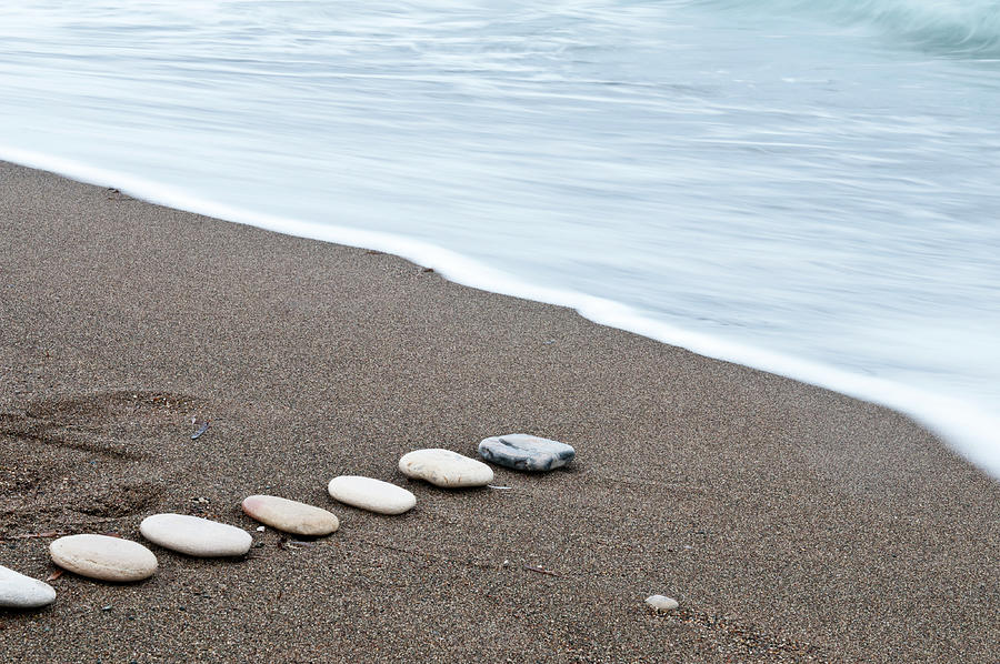 Smooth Beach Stones In A Raw On A Sandy Coastline And Foam Of Sea Water. Photograph