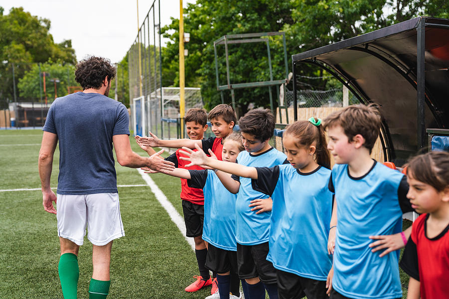 Soccer team of kids high five their coach #1 Photograph by FilippoBacci