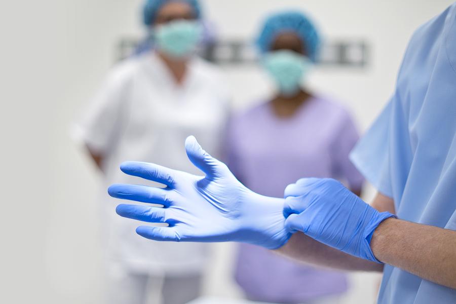 Surgeon putting on latex glove #1 Photograph by Science Photo Library
