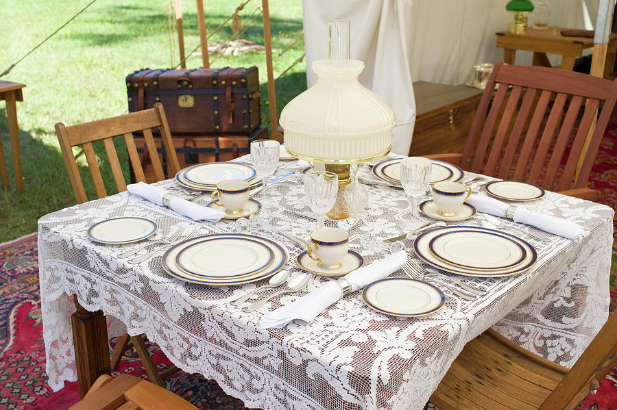 Table set with fine china flatware and crystal glasses on lace table cloth under white canvas awning #1 Photograph by David L Moore