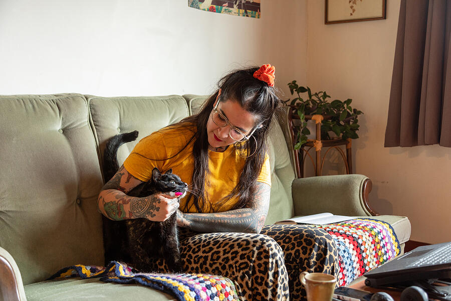 Tattooed woman sitting on a sofa holding a cat #1 Photograph by Jessie Casson