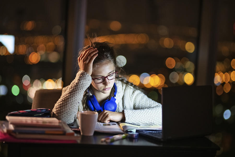 Teenage girl doing homework at night #1 Photograph by Imgorthand