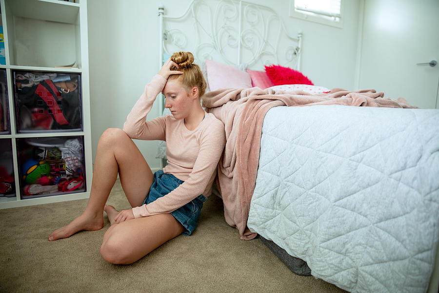 Teenage girl in her bedroom on devices, showing a range of emotions including happiness and saddness. #1 Photograph by Belinda  Howell