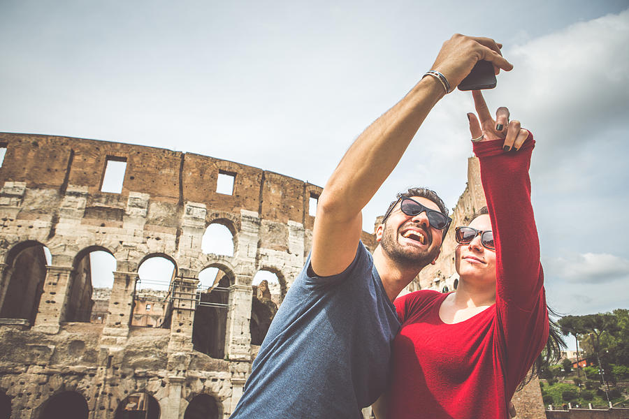 Tourist couple taking a selfie in front of the Coliseum #1 Photograph by Piola666