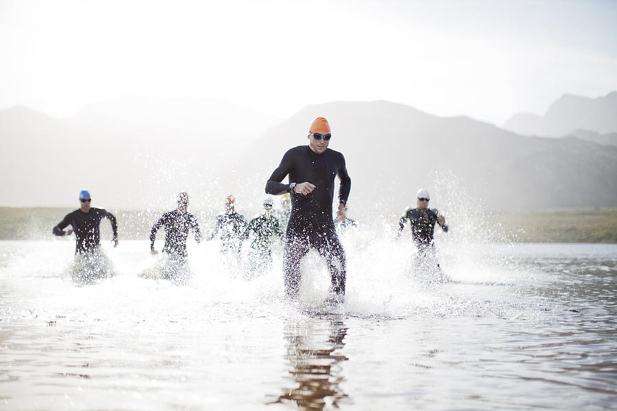 Triathletes emerging from water #1 Photograph by Caia Image