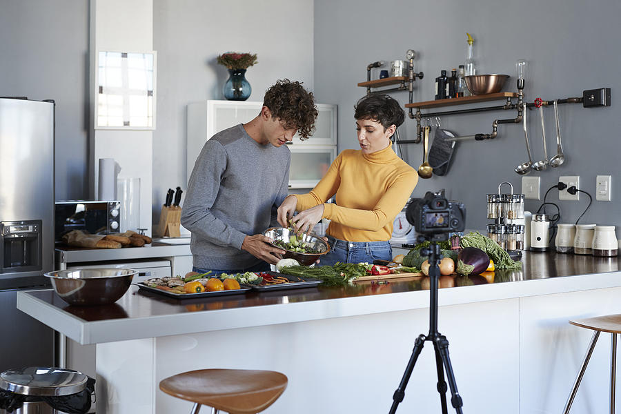 Two food vloggers making video while prepping vegetables in kitchen #1 Photograph by Klaus Vedfelt