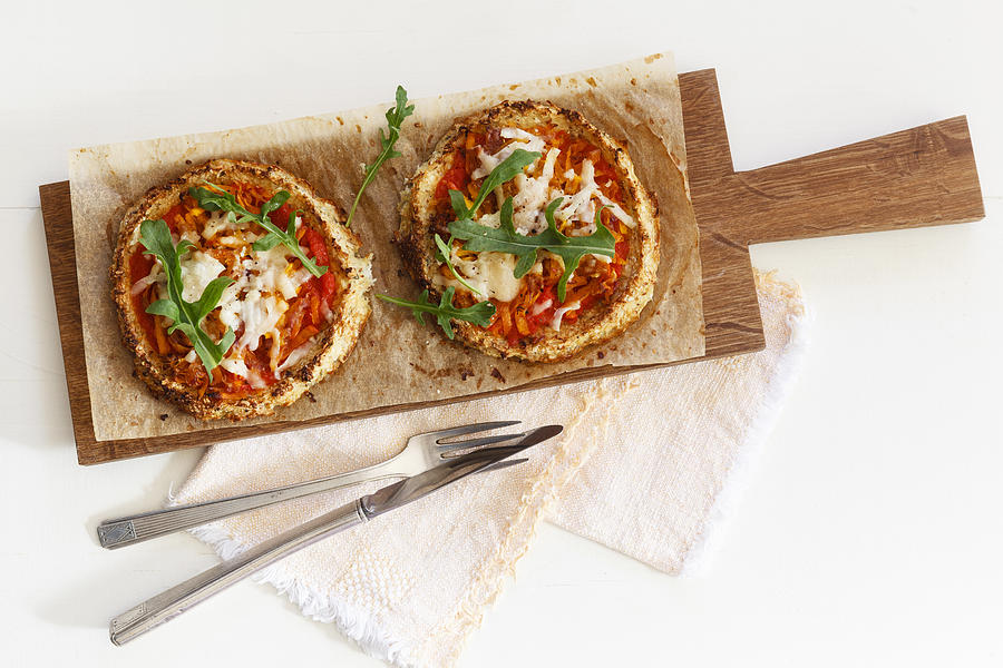 Two homemade glutenfree mini pizzas with cauliflower, pumpkin and rocket on wooden board #1 Photograph by Westend61