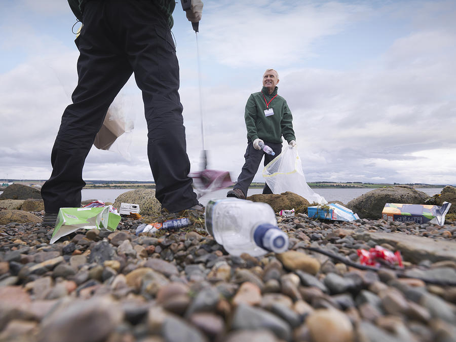 Two male environmentalists removing litter from seashore #1 Photograph by Monty Rakusen