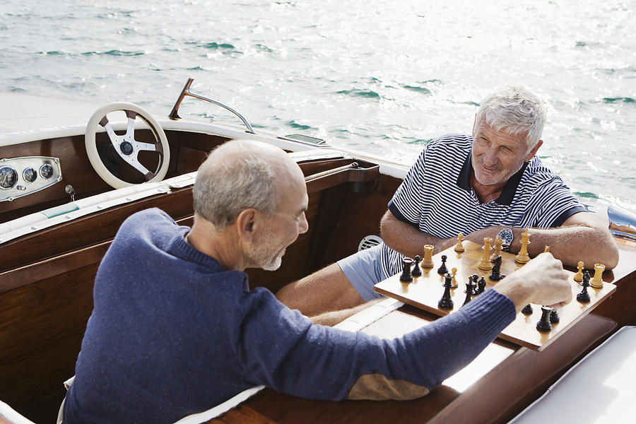 Two senior friends playing chess in motorboat #1 Photograph by Felix Wirth