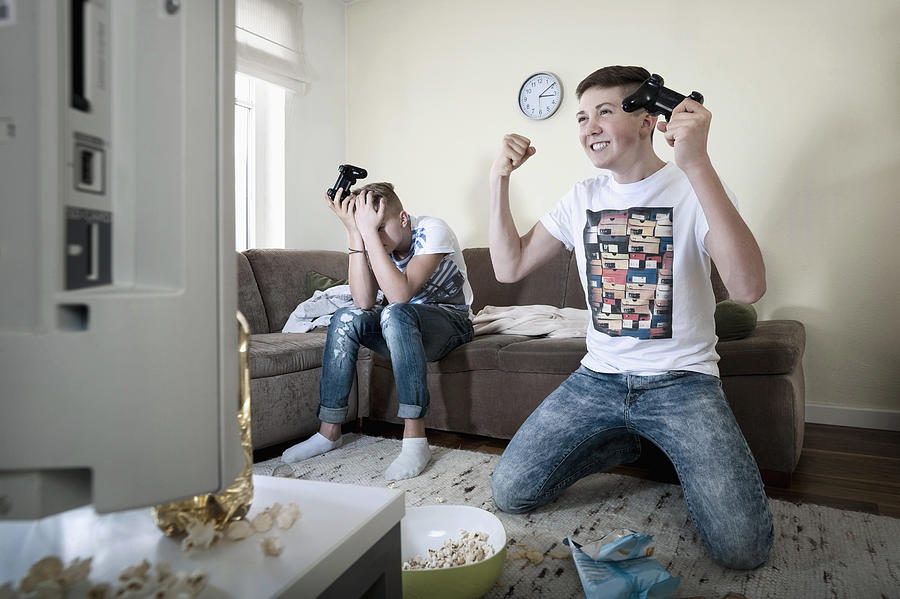 Two teenage boys playing video game #1 Photograph by Robert Niedring