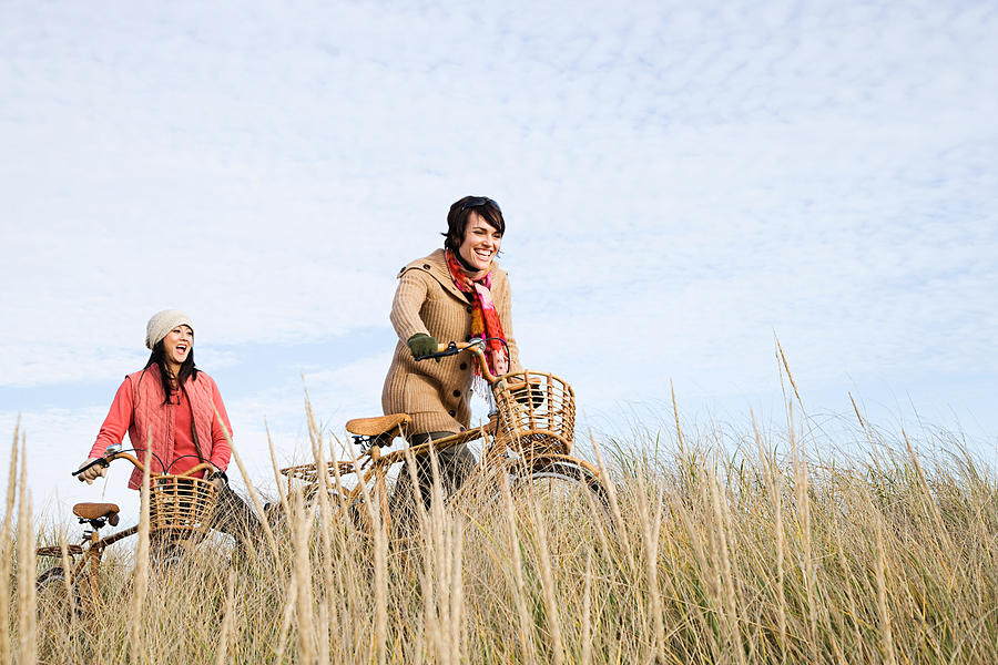Two women in field with bicycles #1 Photograph by Image Source