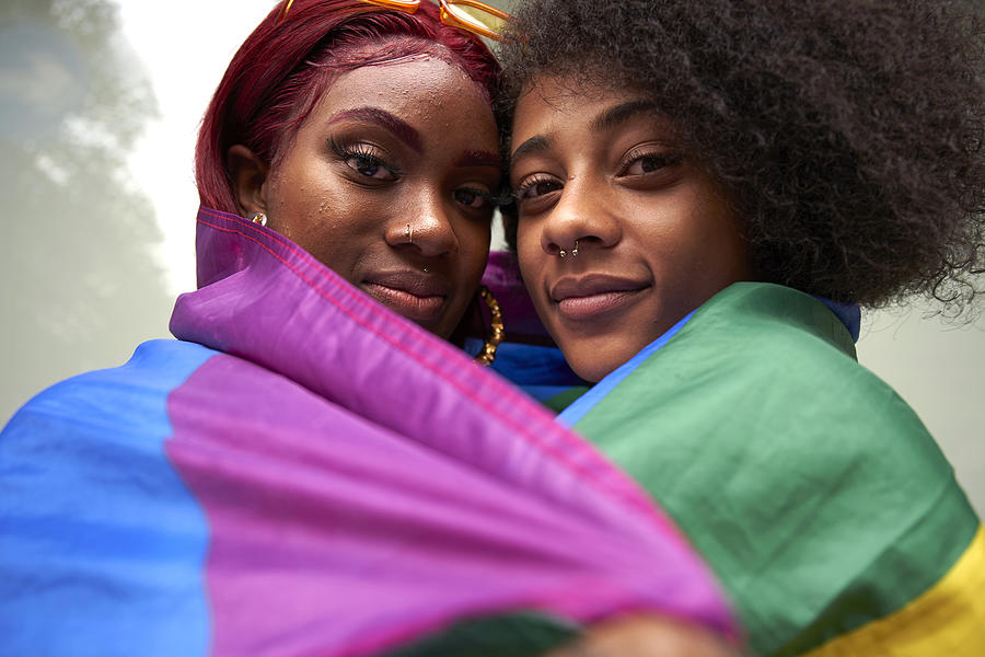 Two women wrapped in Pride Flag #1 Photograph by We Are