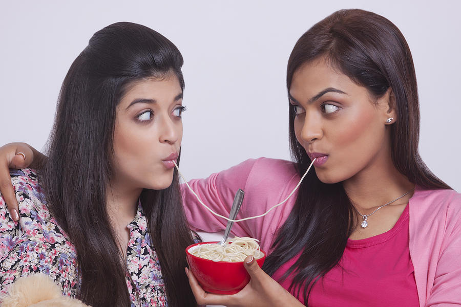 Two young women eating noodles #1 Photograph by Sudipta Halder