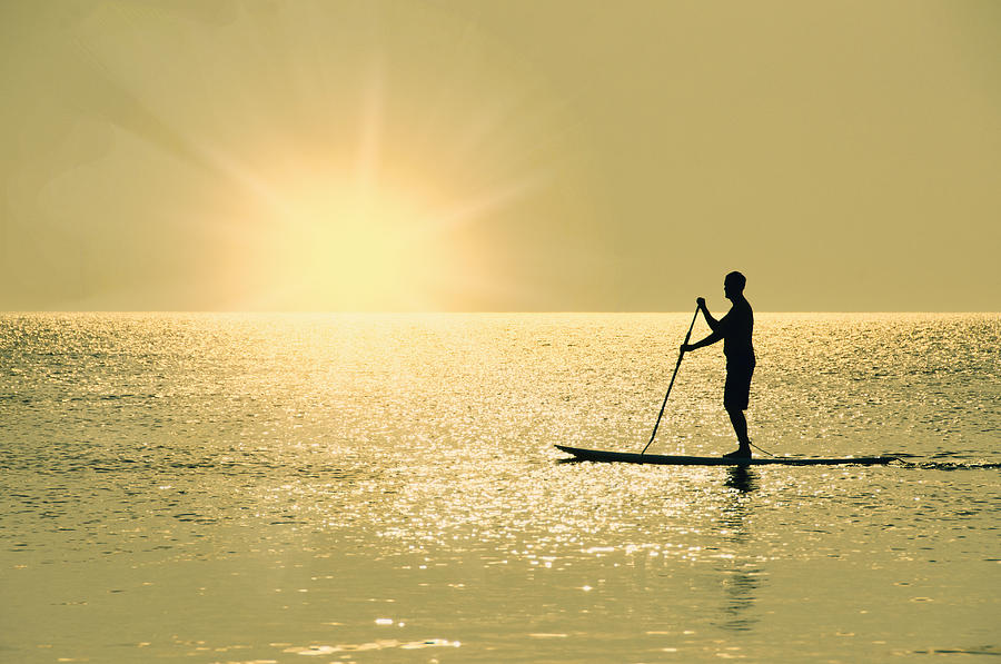 USA, North Carolina, Nags Head, Man standing on paddle board at sunset #1 Photograph by Tetra Images