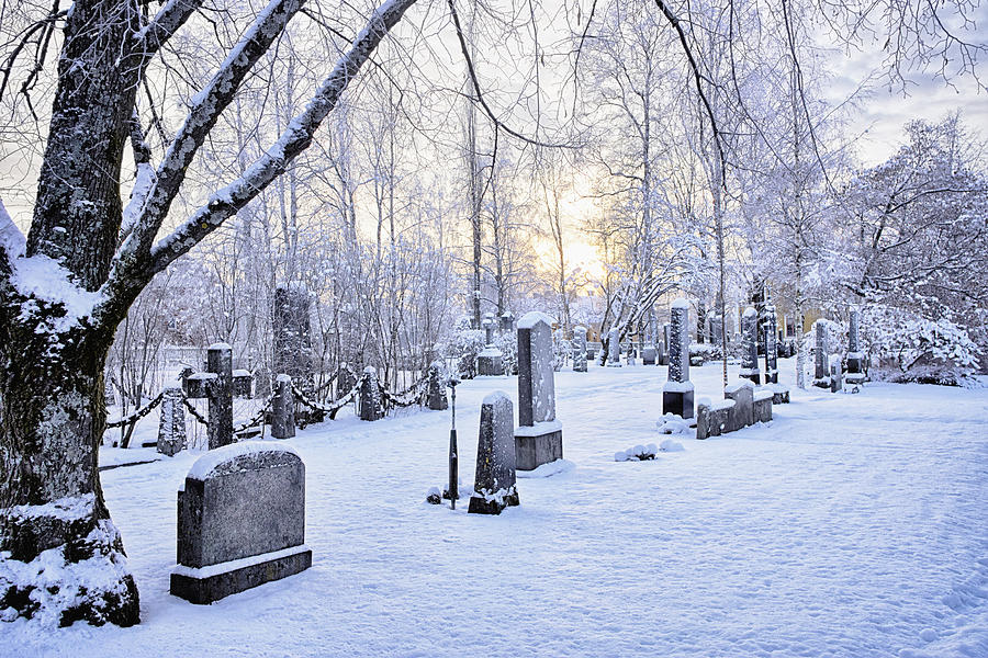 View of grave stones in snow covered cemetery at dusk, Hemavan, Sweden #1 Photograph by Frank and Helena