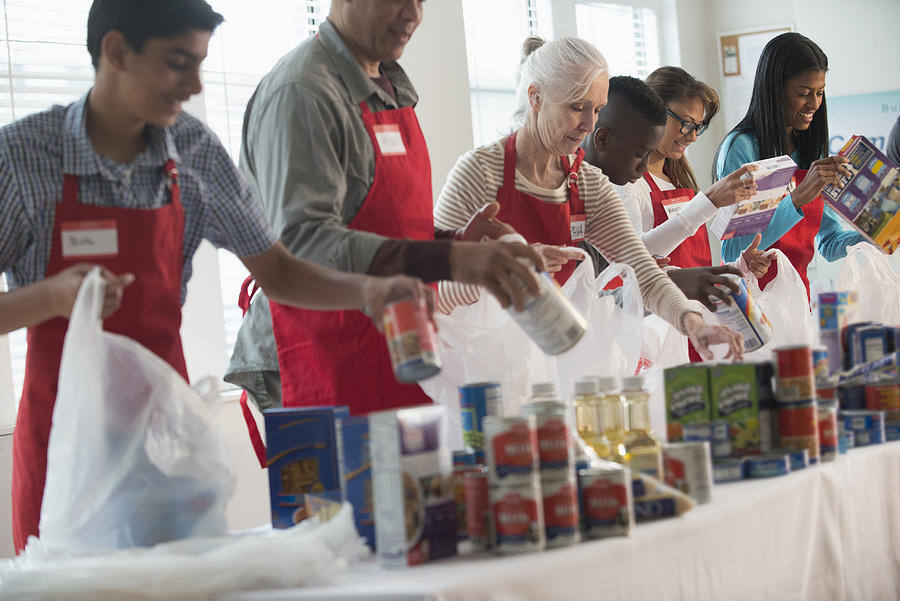 Volunteers packing canned goods at food drive Photograph by Jose Luis Pelaez Inc