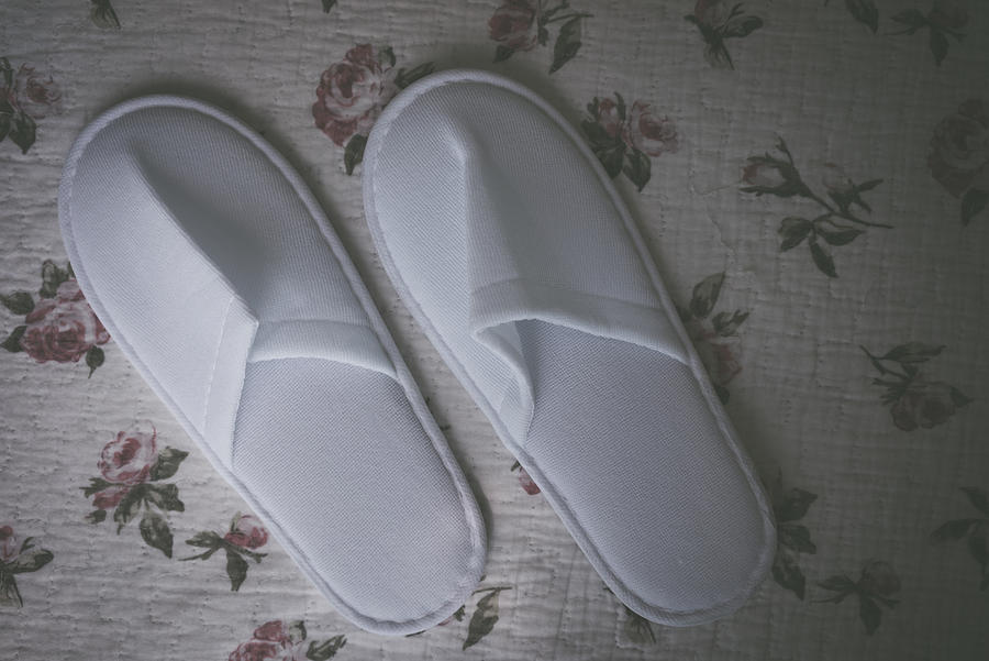 White towelling hotel disposable slippers over old and rust bed-sheet #1 Photograph by Shaifulzamri