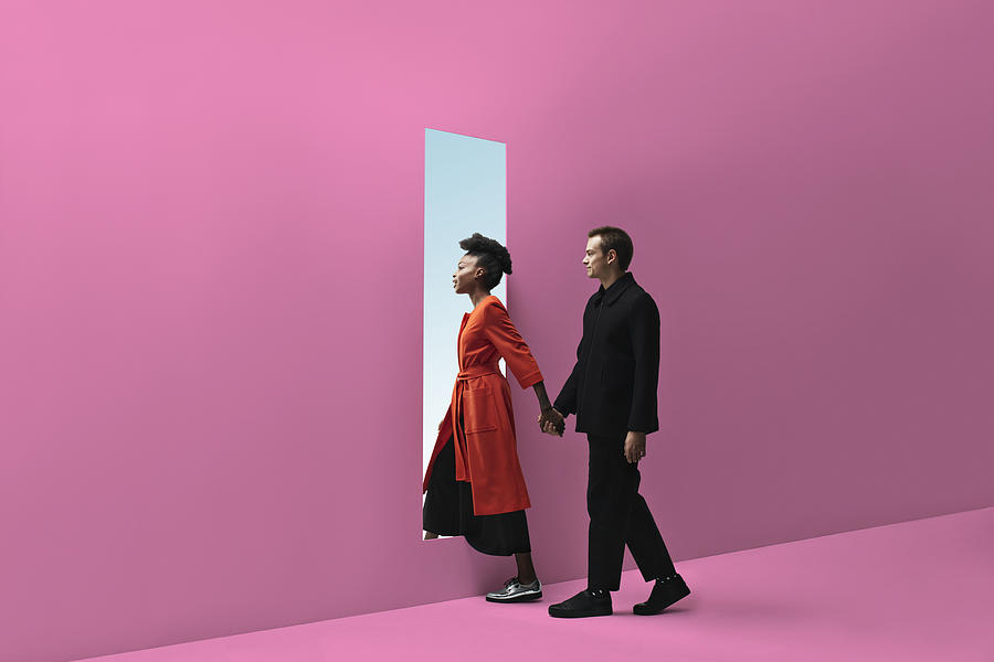 Woman & man holding hands, approaching rectangular opening in coloured wall #1 Photograph by Klaus Vedfelt