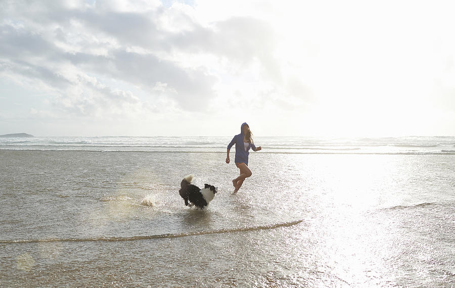 Woman and dog playing at beach. #1 Photograph by Dougal Waters