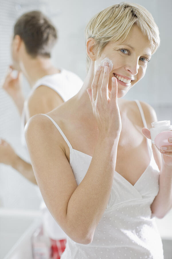 Woman applying face cream in the morning #1 Photograph by Paul Bradbury