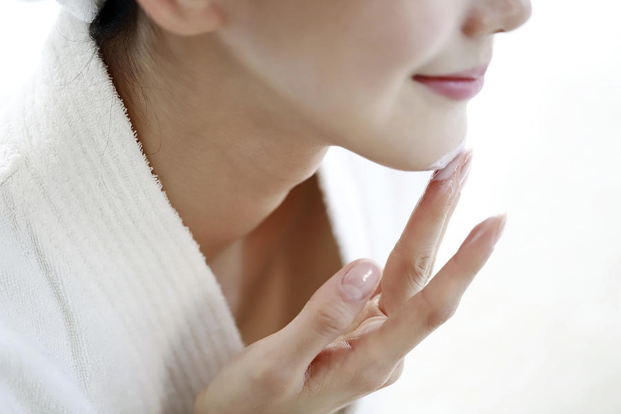 Woman applying moisturizer on face #1 Photograph by Runstudio