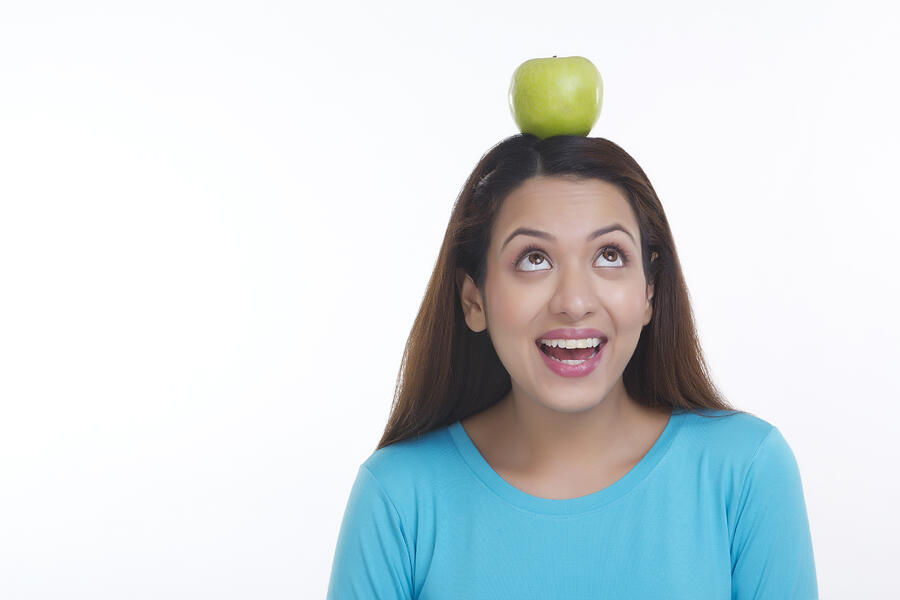 Woman balancing apple on head #1 Photograph by IndiaPix/IndiaPicture